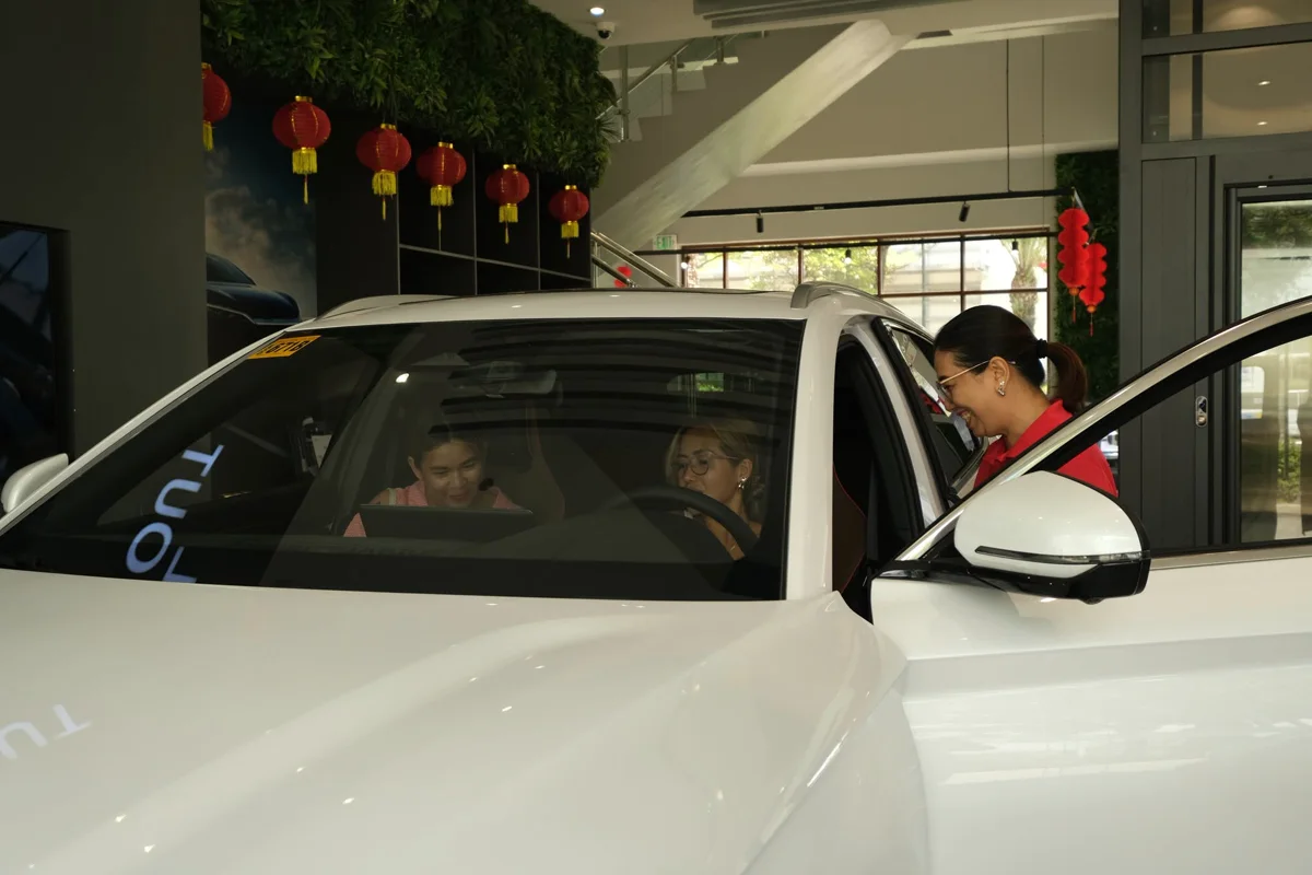 Two customers trying the driver's seat and touchscreen of a BYD