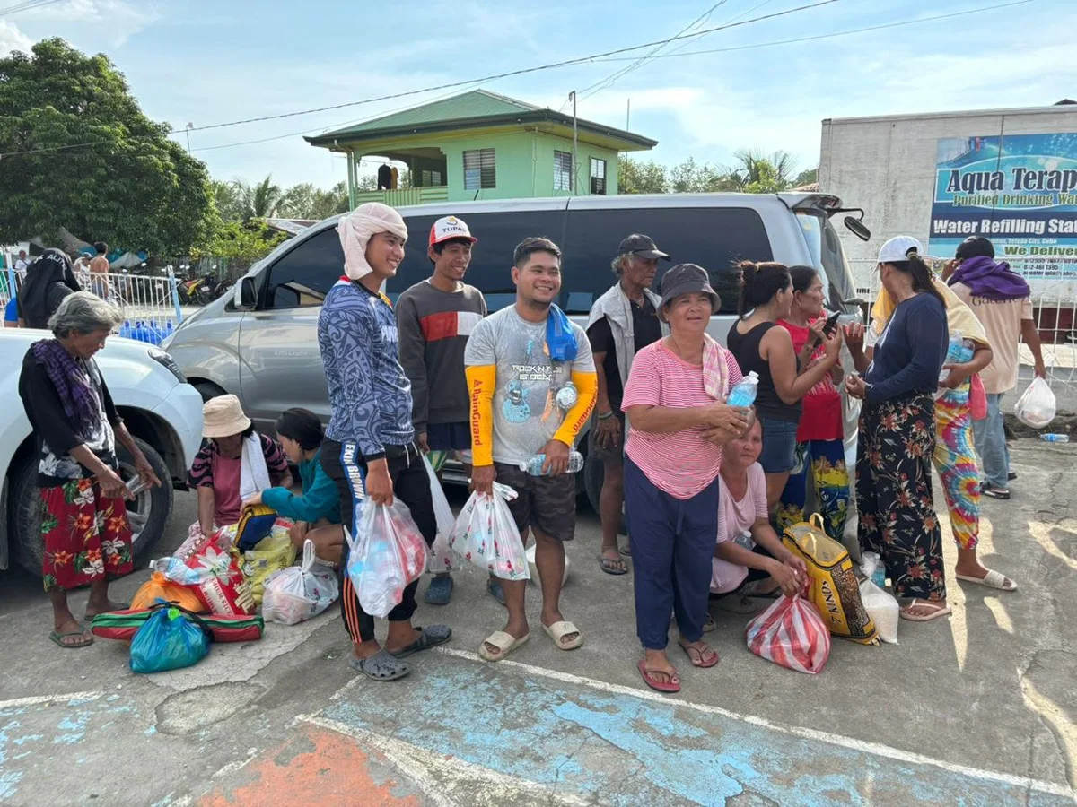 Residents queuing beside vehicles to receive relief goods